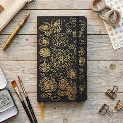 Close-up of gold butterfly and floral design on black faux PU leather notebook cover
